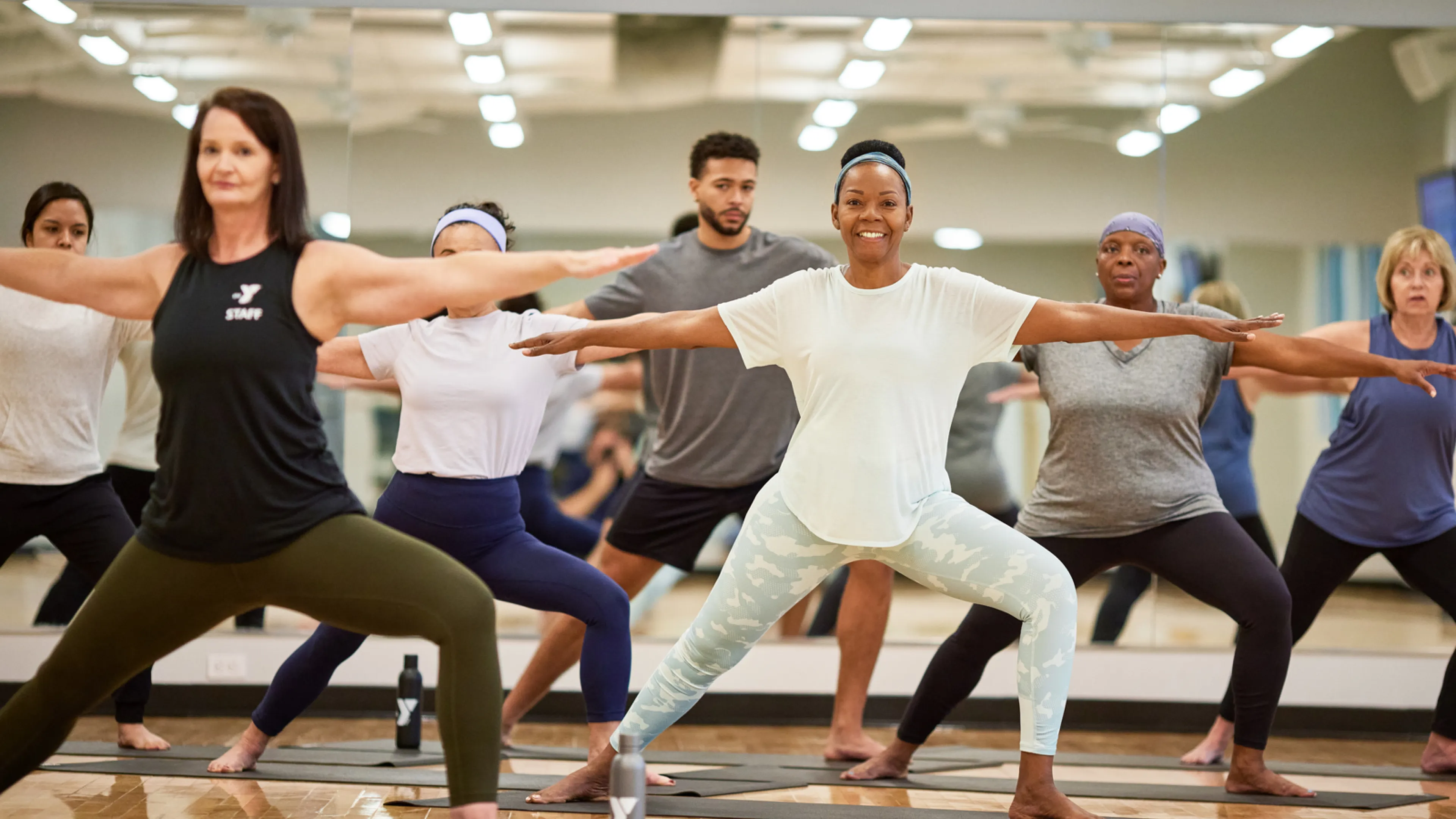 Y staff class leader and six workout class attendees stand and stretch before beginning the workout class; Find Your Y Photography