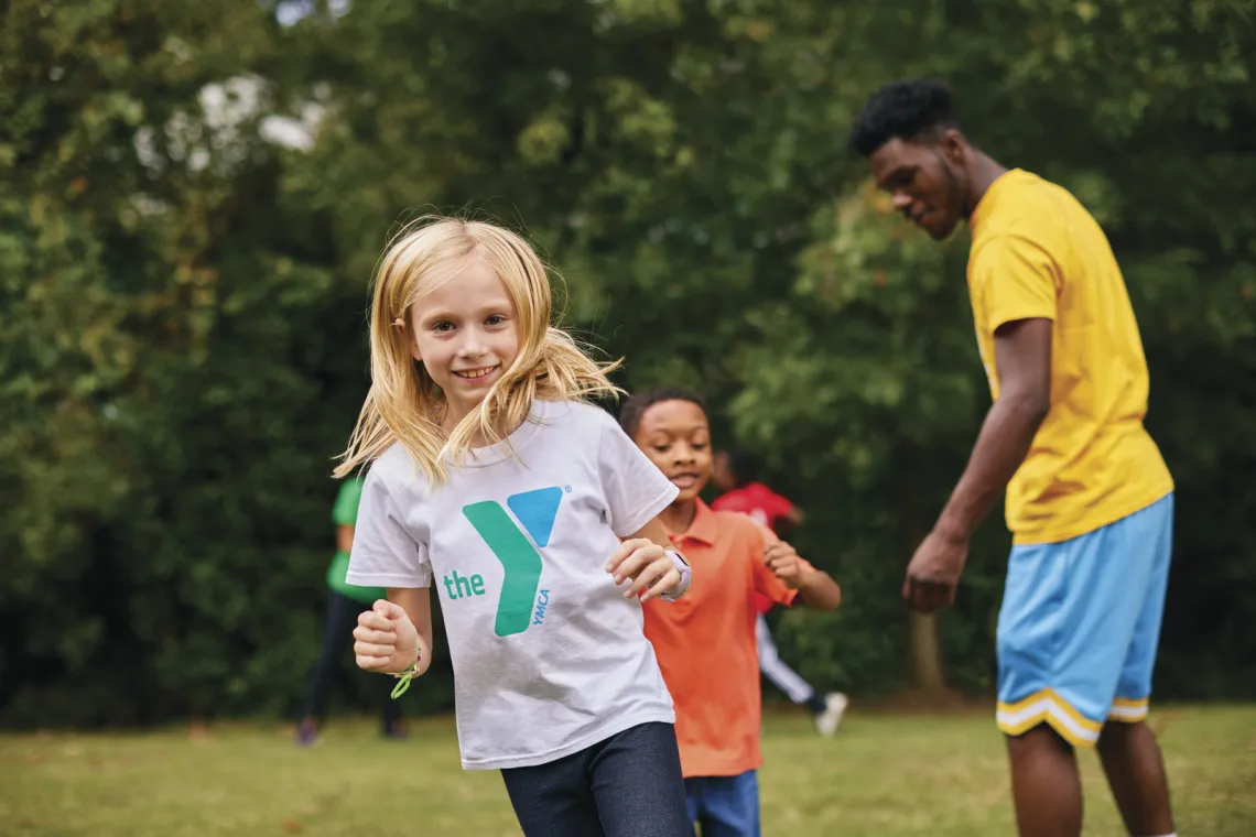 Smiling young children run to complete an obstacle course outside that was set up by Y staff members. Find Your Y